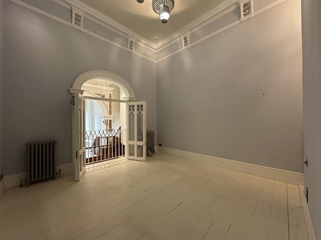 Double doors open to a viewing balcony in this upper floor room within the property.