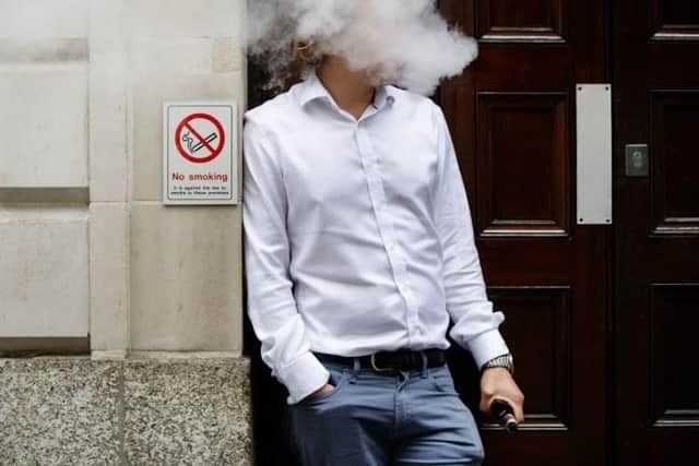 A smoker is engulfed by vapours as he smokes an electronic vaping machine.
