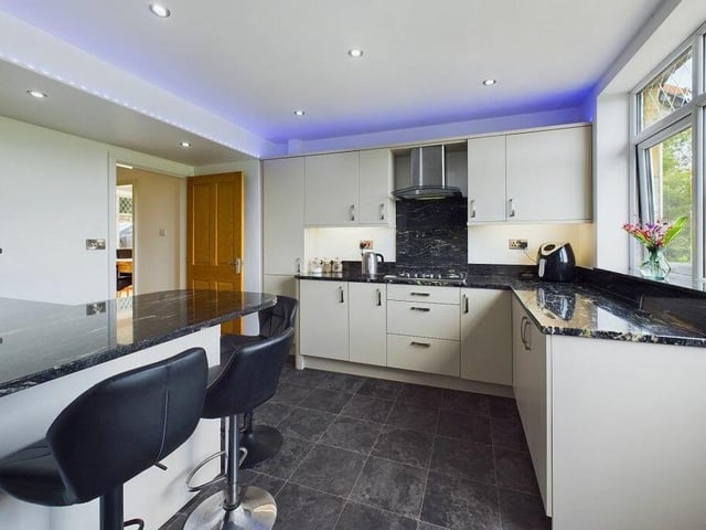 A modern kitchen, with breakfast bar and granite worktops, has stunning views from its window.