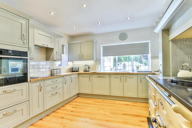 A contemporary style kitchen has fitted, pale green units and oak work tops. An Aga range cooker has a built-in electric oven and an electric hob with extractor, and there's an integral dishwasher.