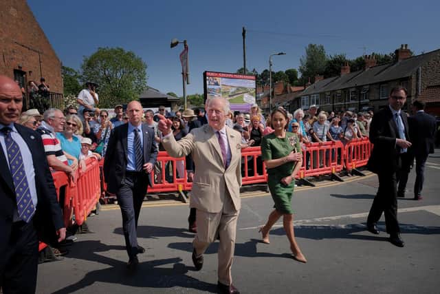 King Charles waves to the crowd during his visit