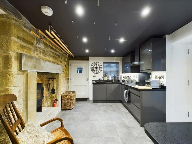 A large stone fireplace holds a warming stove in the kitchen.