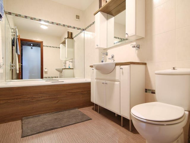 The family bathroom is modern in style and is generously sized to comprise a bath, toilet and wash basin, and vanity storage.