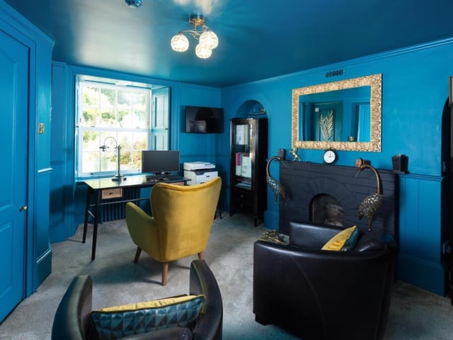This reception room, with feature fireplace and original shutters, is currently used as an office.