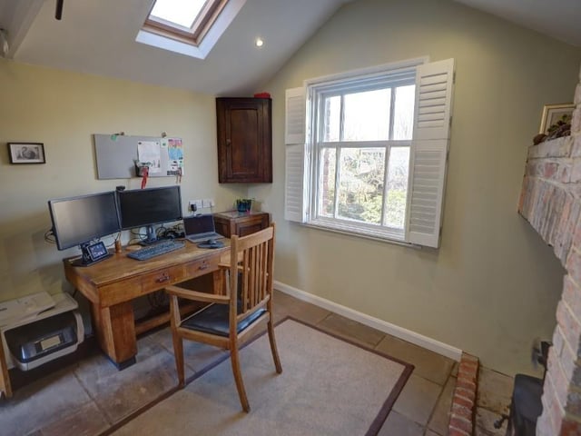 A study with brick fireplace has views over the garden.