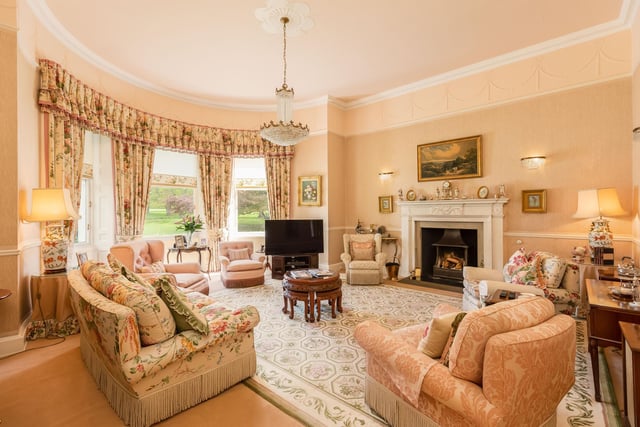 A sitting room with decorative features and a beautiful large bay window showcasing the grounds while bringing in plenty of natural light.