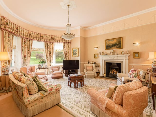 A sitting room with decorative features and a beautiful large bay window showcasing the grounds while bringing in plenty of natural light.