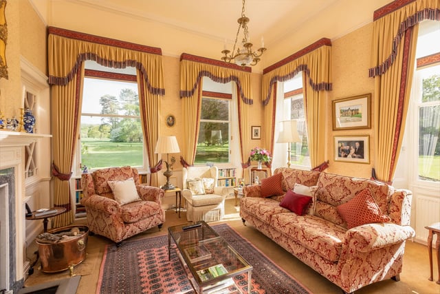 Sash windows give lovely views in this bright morning room, with seating arranged around the large fireplace.
