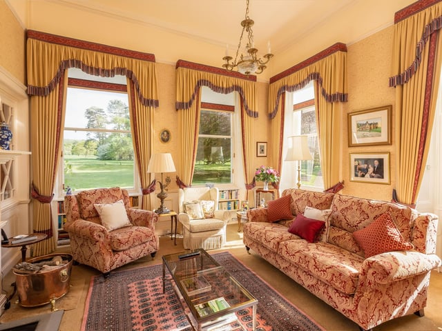 Sash windows give lovely views in this bright morning room, with seating arranged around the large fireplace.
