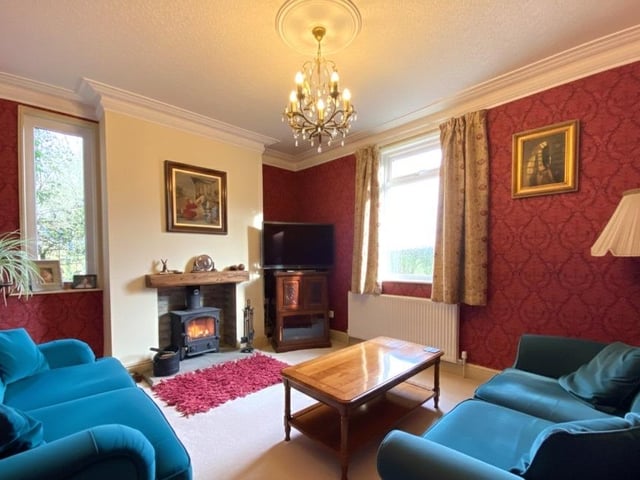 A lovely double-aspect lounge has a log burner within a fireplace setting.