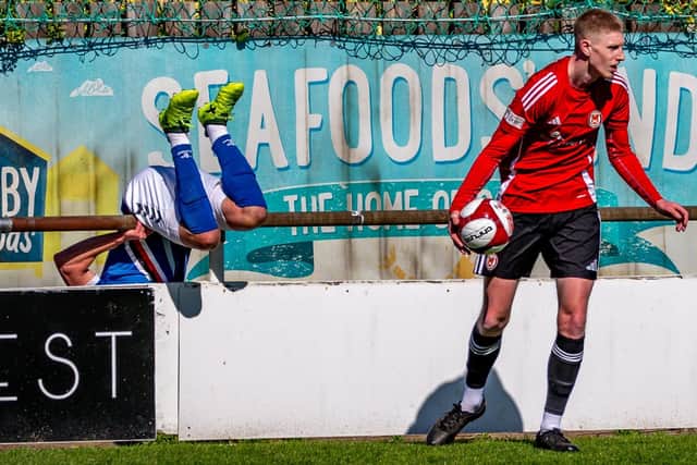 Town striker Jake Charles fails to stop in time and goes over the hoardings at The Towbar Express Stadium. Photo by Brian Murfield
