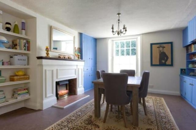 The dining room has built-in shelving and cabinets, and a large feature fireplace with stove.