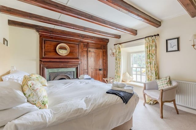 One of the stunning bedrooms, with a period fireplace. Wood panels feature above the fireplace and around the door.
