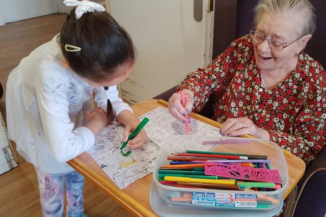 Here a little girl is happily colouring-in with one of the care homes' residents.