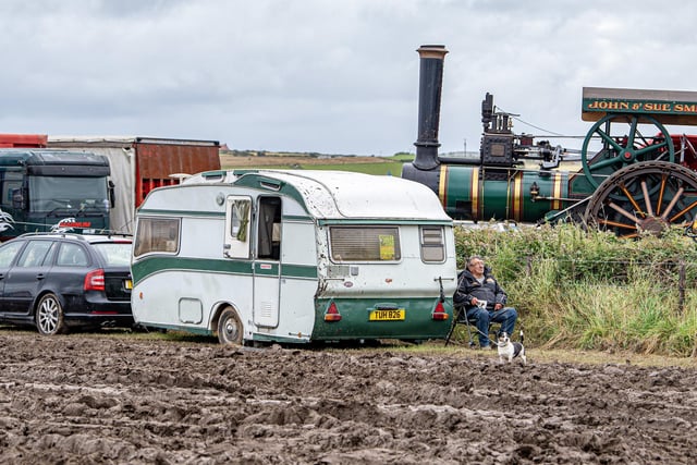 An exhibitor takes a break by his caravan in the mud