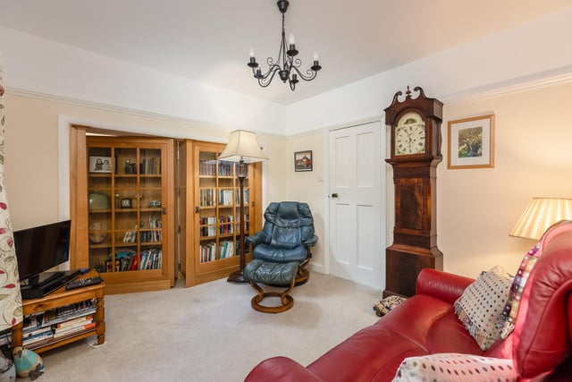The sitting room and snug are divided by a concealed door, or bookcase.