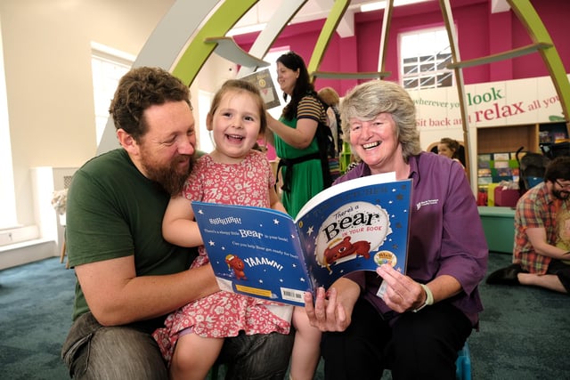 Staff Coralie McGrath reading with visitors in the new children's area!