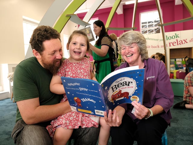 Staff Coralie McGrath reading with visitors in the new children's area!