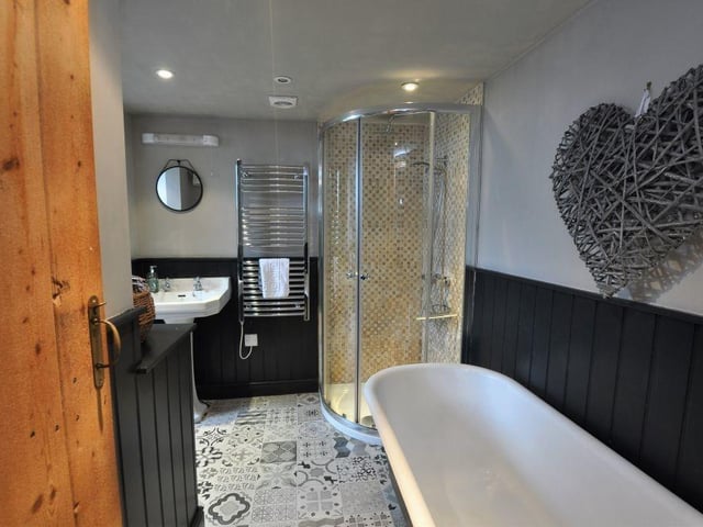 The bathroom has a large free-standing roll-top bathtub, with a separate shower cubicle.