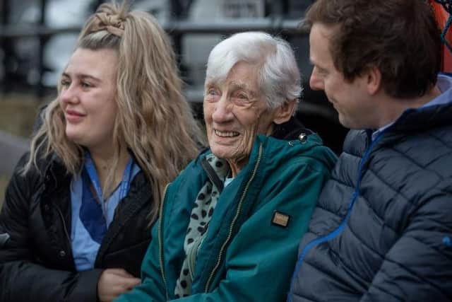 Marjory Hart sitting on a bench with The Mayfield care home staff, enjoying harbour views.