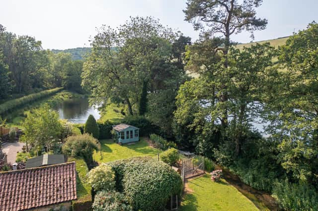 The picturesque gardens of the property, with ponds and open countryside beyond.