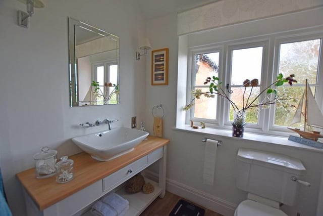 A bathroom with wash basin and vanity unit as part of the suite.