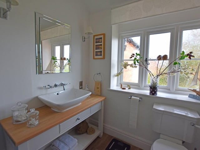 A bathroom with wash basin and vanity unit as part of the suite.