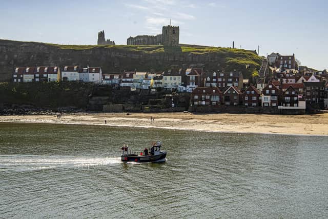 A fishing boat returns back to Whitby harbour in fine weather.