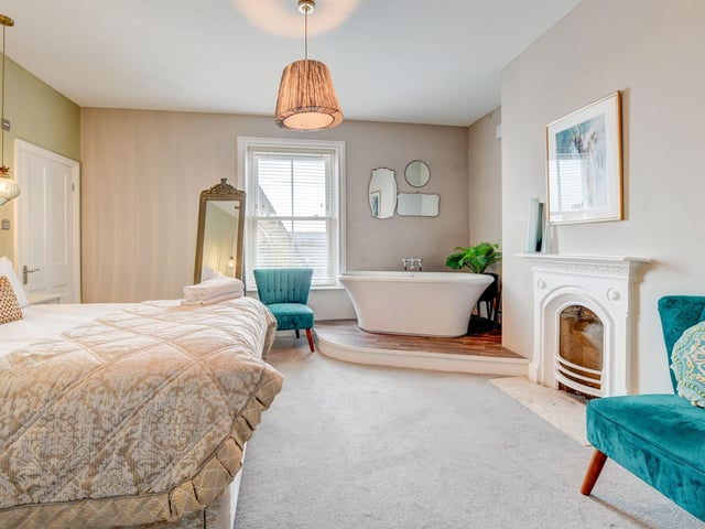 Many bedrooms have en suite facilities and this one has a free standing bath on a plinth, along with a feature fireplace.