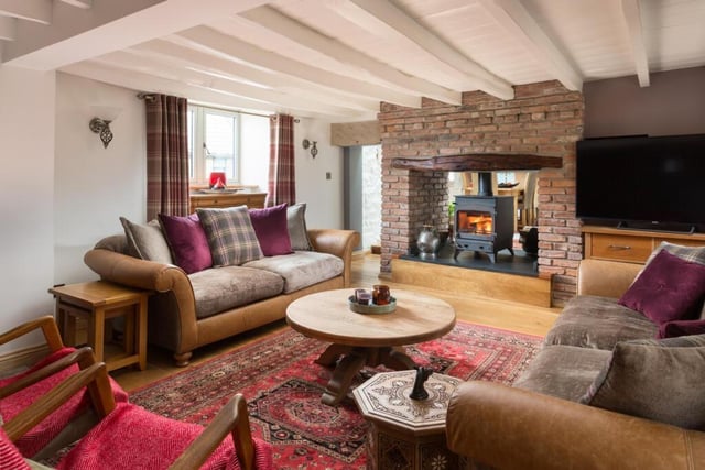 The spacious sitting room with double sided brick fireplace and wood burner.