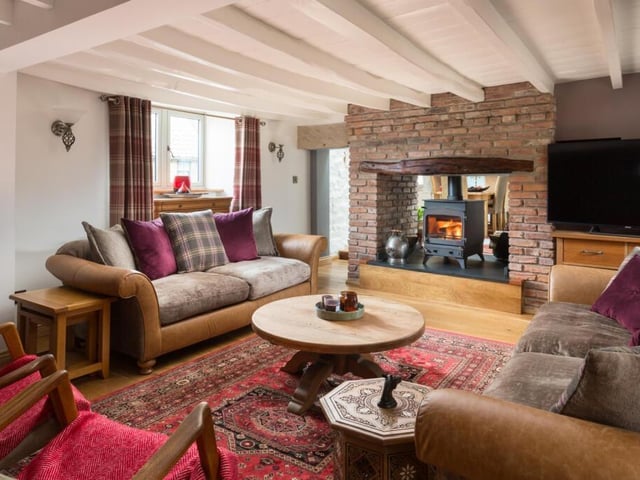 The spacious sitting room with double sided brick fireplace and wood burner.
