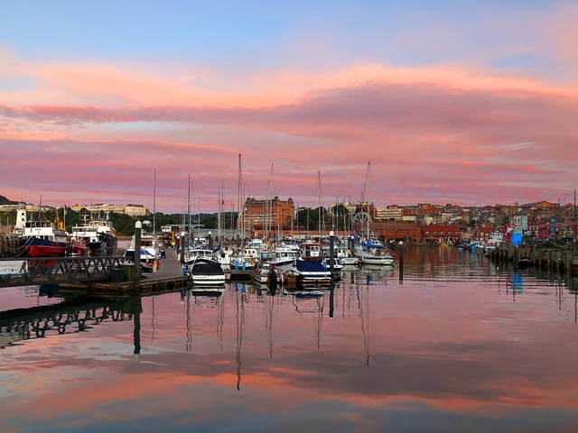 Tranquil harbour with rainbow skies.