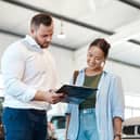 A car buyer discusses finance options with a dealership representative. New research suggests many UK drivers now regret the car finance deals they agreed to in the past decade.