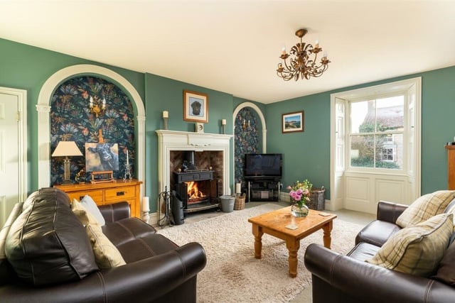 The bay-fronted sitting room with feature fireplace and stove.