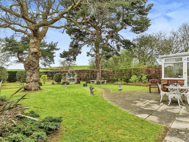 The lovely lawned garden with patio area has an open outlook.