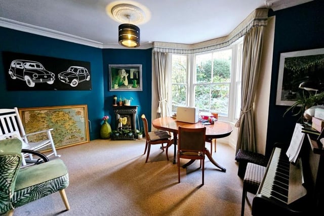 A deep bay window is used as a dining space in this room with period fireplace.