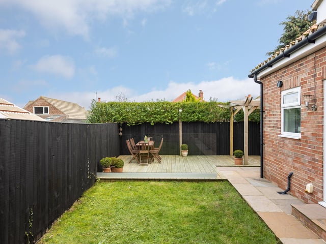 The house has wrap-around gardens with a patio seating area.