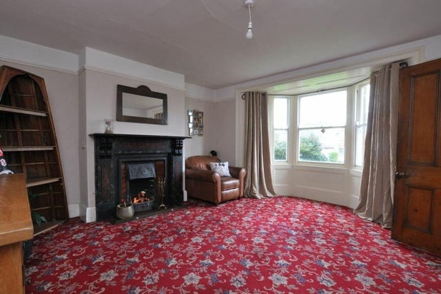 A second bay-fronted reception room has a central, open fireplace as a focal point.