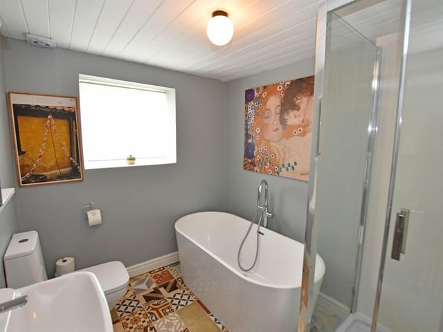 A modern bathroom with free-standing bath tub, and shower unit.