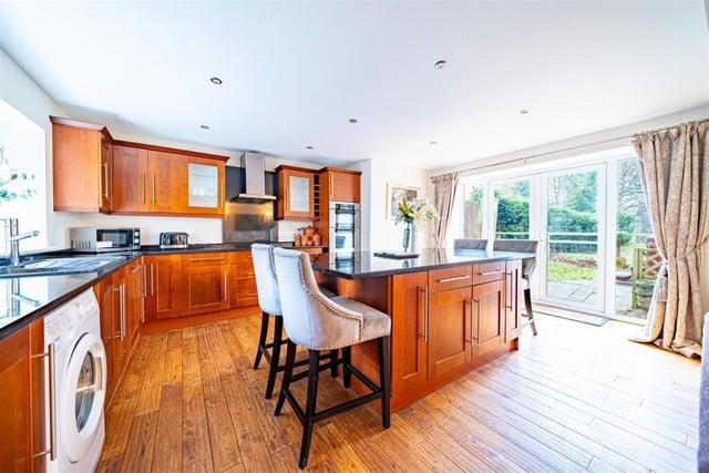 A spacious kitchen, with central island, has doors leading outside.
