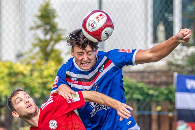 Defender Harrison Beeden wins a header for the home side.