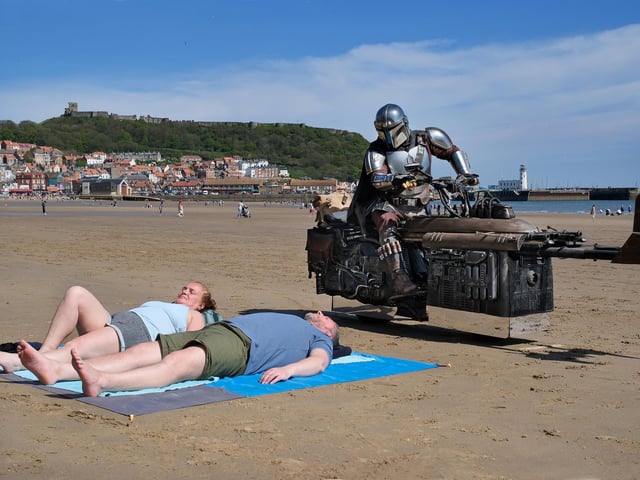 The Mandalorian rides past a couple enjoying the Scarborough sunshine.