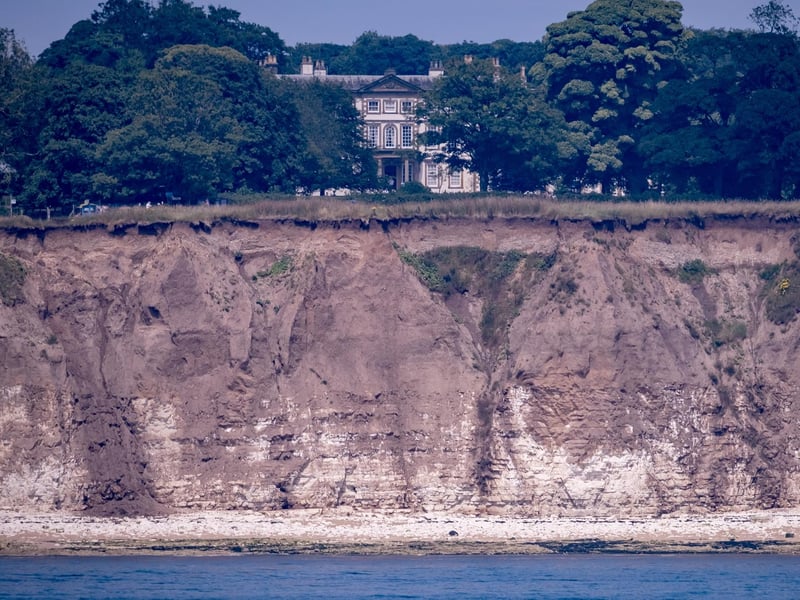 A stunning shot of the historic house, with the dramatic cliffs in the foreground.