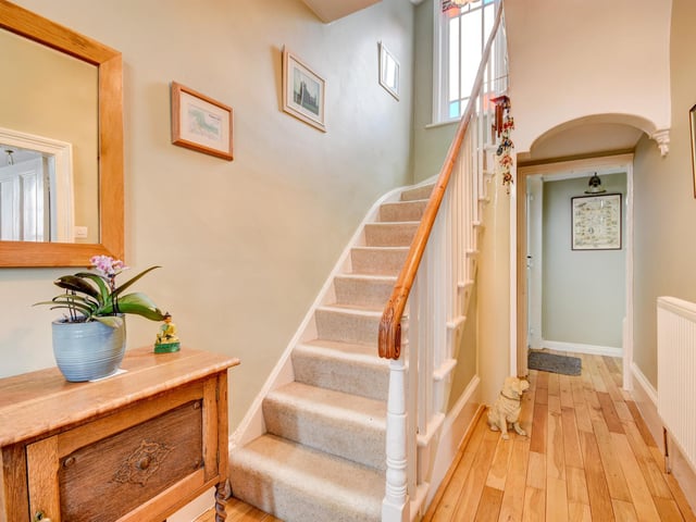 A light, inviting hallway with stained glass window above.