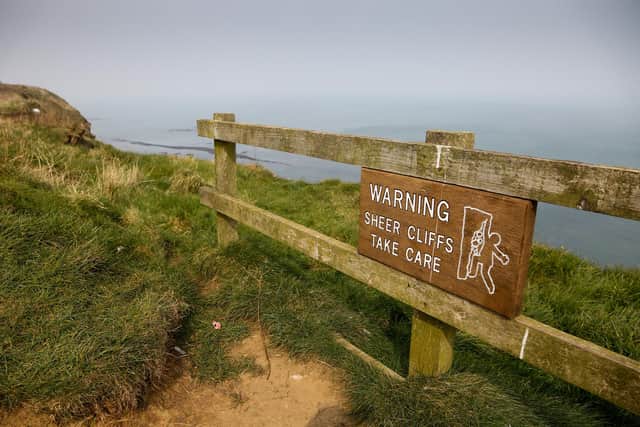 Signs on the cliff top at Filey near the Blue Dolphin Holiday Park, warning the public of the dangers of the sheer cliffs.