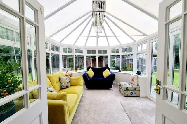 The conservatory is surrounded by garden, with doors leading outside.