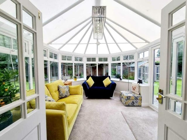 The conservatory is surrounded by garden, with doors leading outside.