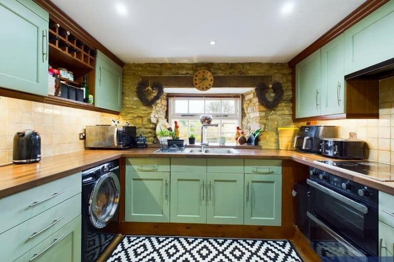 The country style kitchen has fitted units and an exposed brick wall.