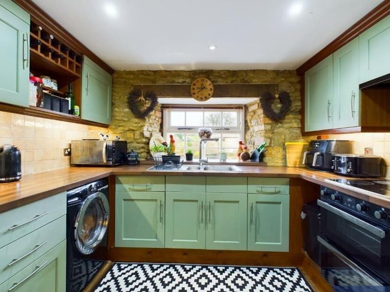 The country style kitchen has fitted units and an exposed brick wall.