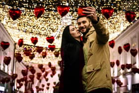 A couple poses for a selfie under heart-shaped balloons displayed for Valentine's Day in downtown Moscow on February 13, 2020. (Photo by Dimitar DILKOFF / AFP) (Photo by DIMITAR DILKOFF/AFP via Getty Images)